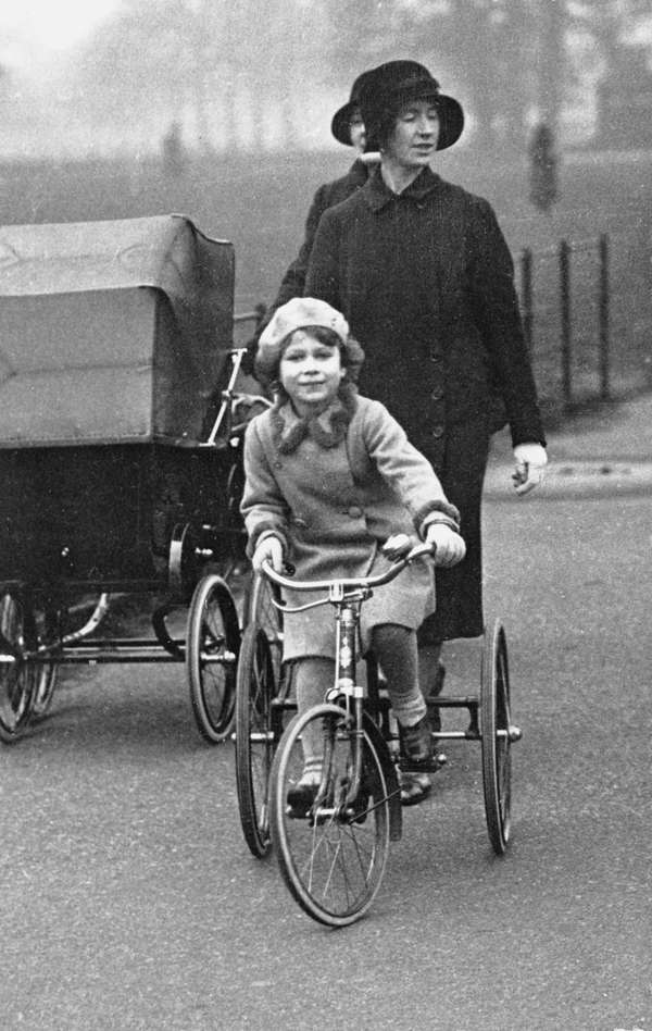 Princess Elizabeth accompanied by her nurse, riding her tricycle in Hyde Park, London. (undated photo)