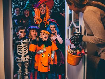 Group of children and their parents playing trick or treat on Halloween.