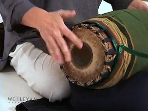 See a man playing the mridangam drum of the Karnatak music tradition